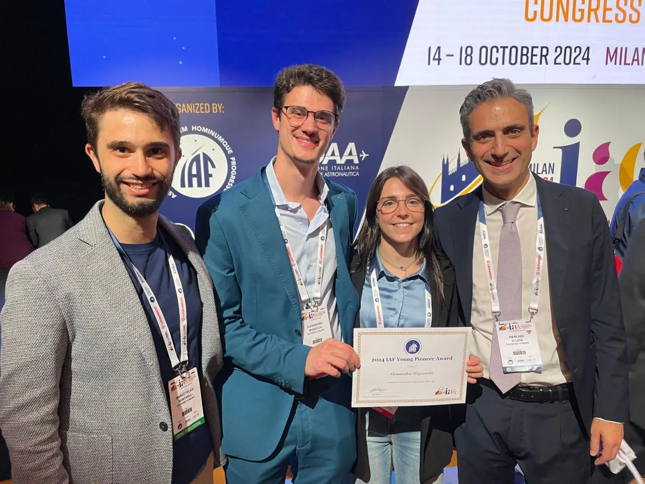 Four people at a conference holding a certificate