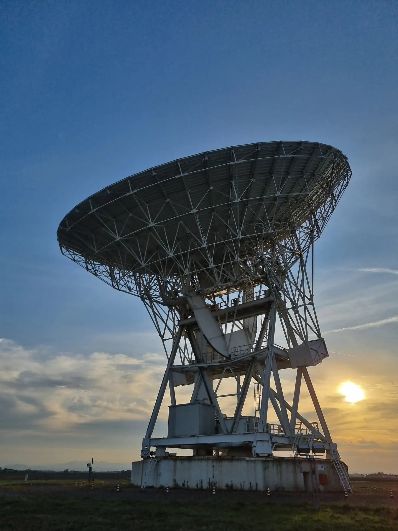 Large radio telescope against a sunset sky